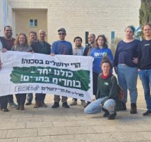 קבוצת אנשים עומדת ומחזיקה שלט.