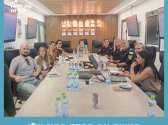 תמונה של מספר אנשים יושבים ליד שולחן ארוך